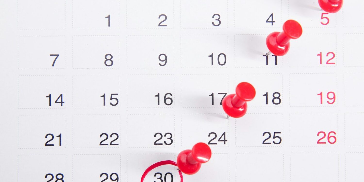 a calendar with red push buttons pinned to it
